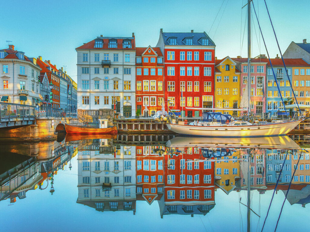 Sunrise Over Nyhavn in Copenhagen, Denmark: A Serene Morning with Vibrant Historic Buildings Mirrored in the Still Canal Waters