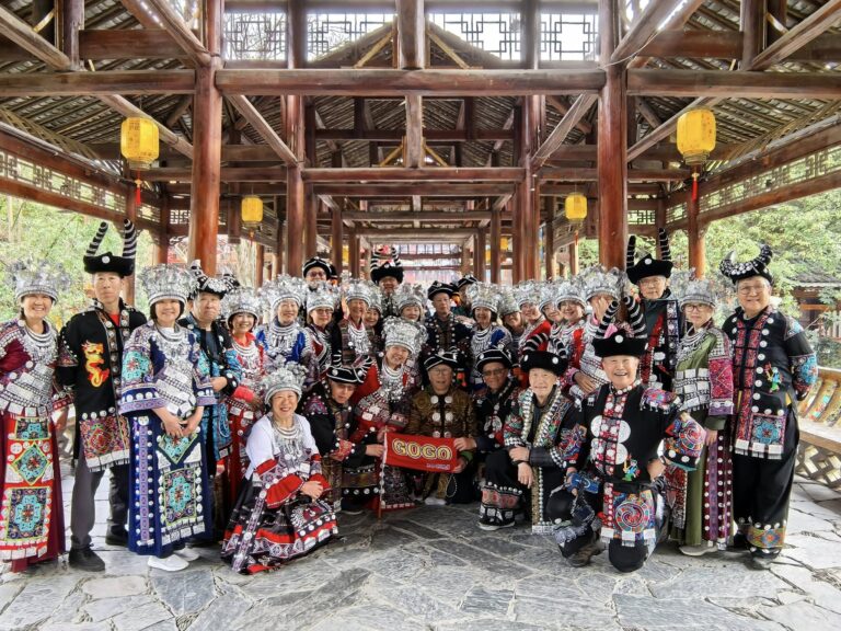 A large group dressed in traditional Miao attire, celebrating the vibrant culture of Xijiang Thousand Household Miao Village