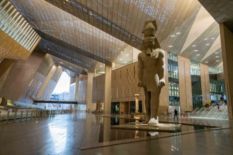Interior of the Grand Egyptian Museum featuring a large pharaoh statue.