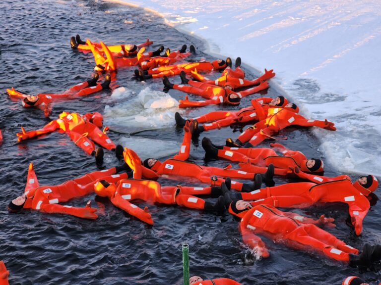 Group of GoGo Tours travelers wearing survival suits and floating in icy waters during the Arctic Circle 9-Day Tour.