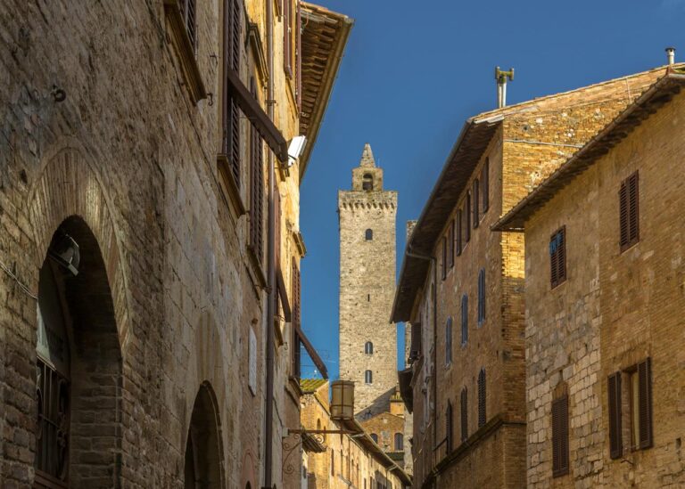 Narrow medieval street in San Gimignano with a tower in the background.