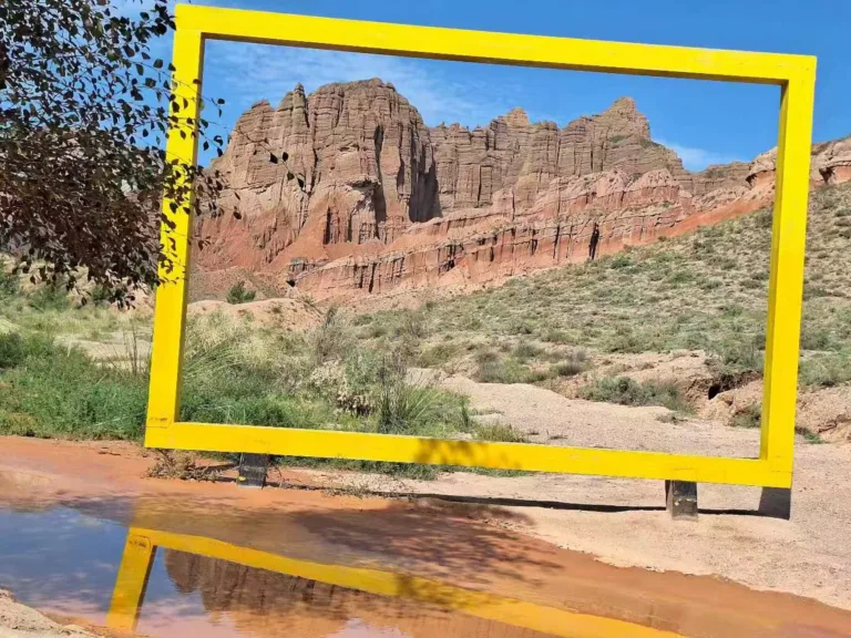 Large yellow picture frame art installation in a red rock desert in Xinjiang